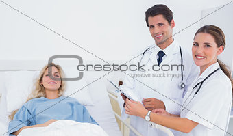 Smiling doctors standing next to a patient