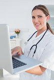 Smiling woman doctor using laptop