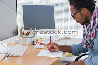 Handsome designer drawing something with a red pencil