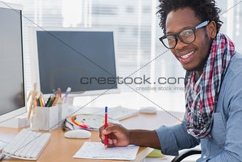 Smiling designer drawing something with a red pencil