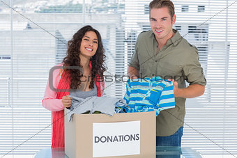 Smiling volunteers taking out clothes from donations box