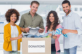 Smiling team of volunteers taking out clothes from a donation box