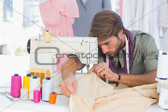 Handsome fashion designer sewing