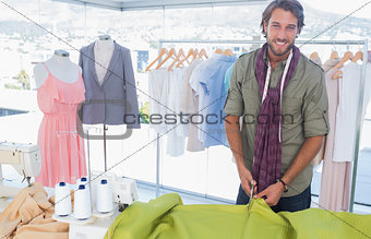 Handsome fashion designer cutting textile