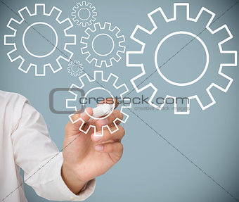 Businessman drawing cogs and wheels