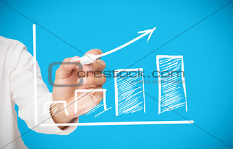 Businessman drawing white arrow above graph
