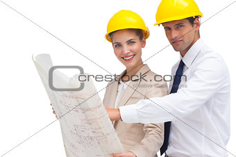 Architects with construction plan and yellow helmets
