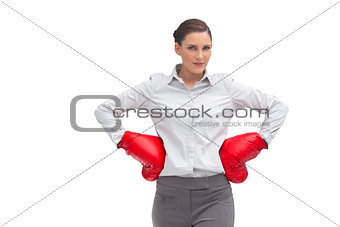 Businesswoman with hands on hips wearing boxing gloves