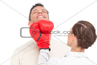 Businesswoman wearing boxing gloves punching businessman