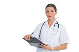 Serious nurse holding clipboard and looking at camera