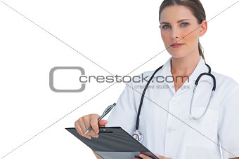 Unsmiling nurse holding clipboard and looking at camera