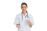 Serious nurse holding medicine and glass of water