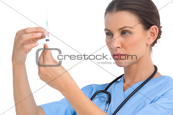 Serious surgeon holding up a needle and checking it