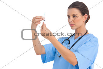 Serious surgeon holding up needle and checking it