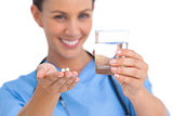 Smiling surgeon holding medicine and glass of water