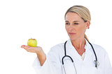 Smiling doctor holding apple and looking at it
