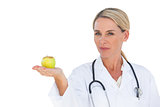 Smiling doctor holding apple and looking at camera