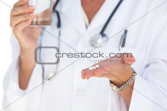 Doctor holding out tablets and water glass