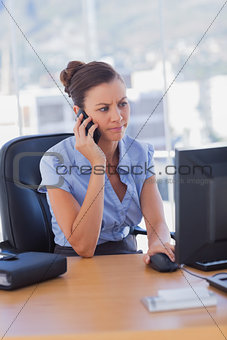 Concentrating businesswoman working on her computer and calling