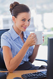 Businesswoman holding coffee mug and smiling