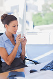 Businesswoman holding her mug and looking at her computer