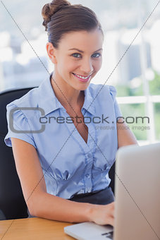 Businesswoman smiling and working on her laptop