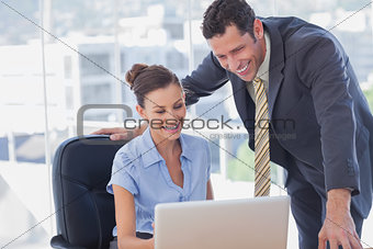 Smiling business people working together with the same laptop