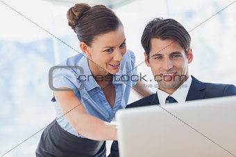 Happy business people looking together at the laptop