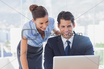 Happy business people looking at laptop and smiling
