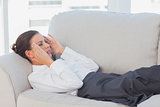 Business woman lying on couch with headache
