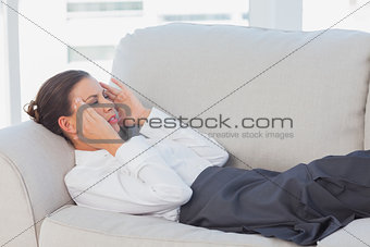Business woman lying on couch with headache