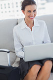 Businesswoman smiling at camera with laptop