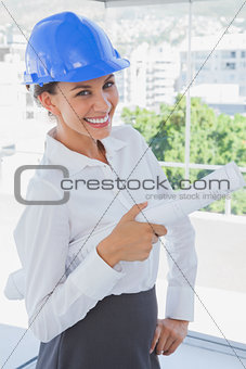 Smiling architect holding plans and wearing hardhat