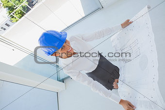 Overhead of a smiling architect holding a blueprint