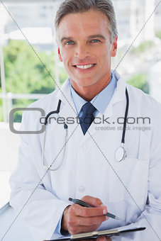 Smiling doctor standing with a clipboard
