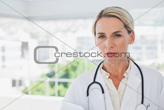 Serious blonde doctor holding a clipboard