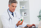 Serious doctor holding a bottle of pills