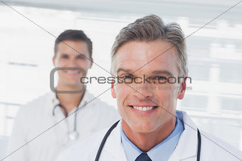 Smiling doctor standing in front of his colleague