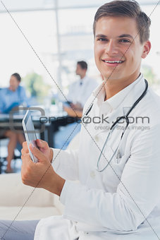 Doctor looking at the camera and using tablet pc