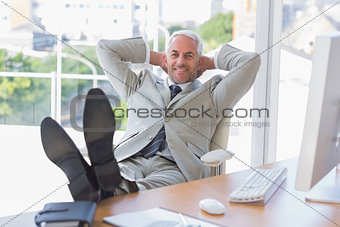 Businessman relaxing at desk and smiling at camera