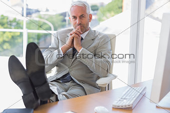 Thoughtful businessman sitting with feet up