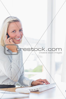 Blonde businesswoman on the phone smiling at camera