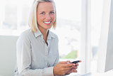 Blonde businesswoman texting and smiling at camera