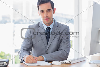 Cheerful businessman writing at his desk