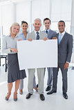 Happy business team holding large blank poster