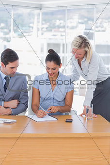 Businesswoman showing colleagues something with notepad