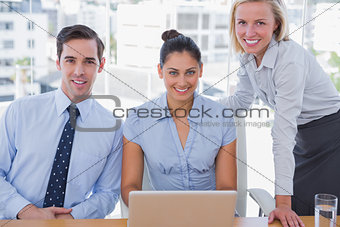 Business team with laptop smiling at camera