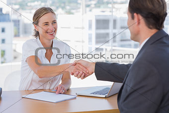 Cheerful interviewer shaking hand of an interviewee