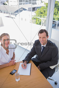 Overhead of cheerful business people taking notes