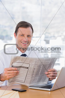 Smiling businessman reading a newspaper